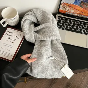 Vista detallada de bufanda de punto gris suave en mesa oscura con accesorios de estilo.