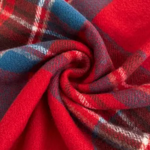 Close-up detailed shot of a soft red and blue plaid winter scarf texture showing fabric quality.