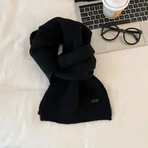 Detail shot of a black knitted winter scarf, cozy warmth and stylish daily wear accessory.