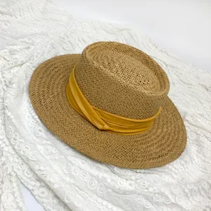 Detailed shot of a stylish women's straw boater hat with a vibrant yellow ribbon.