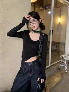 Gros plan sur l'élégant foulard noir à pois blancs, accessoire de mode long et polyvalent.