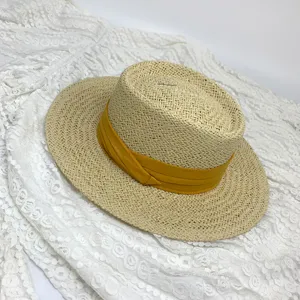 Detail view of the French flat top straw hat with a stylish yellow ribbon band, summer beach wear.