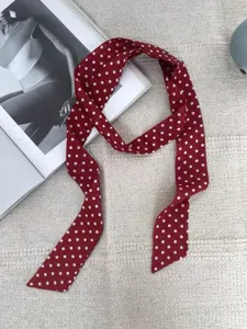 Détail de foulard twilly en soie à pois rouges, long ruban élégant pour décoration de sac à main.