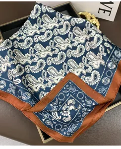 Gros plan d'un foulard en soie paisley bleu avec bordure marron, détail de cou élégant.