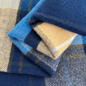 Close-up view showing the soft wool fabric texture and blue plaid pattern of the warm winter scarf.