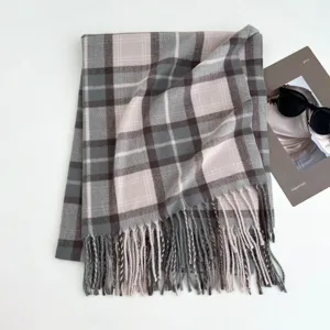 Close-up detail of the classic grey plaid winter scarf with delicate fringe hems and warm texture.