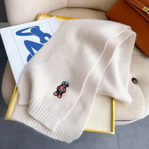 Soft beige wool knit scarf featuring cute embroidered bear detail, cozy winter neck warmer accessory.
