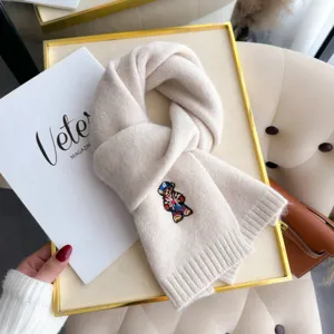 Detailed view of winter beige knitted wool scarf featuring cute bear embroidery and soft cozy fabric.