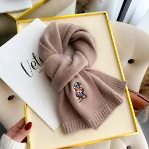 Close-up detail of knitted wool scarf with cute embroidered bear design, warm winter neck wear.