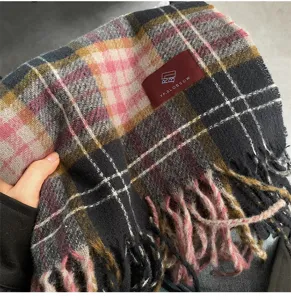 Detailed view of the winter plaid tassel scarf, showing soft fabric texture and label.