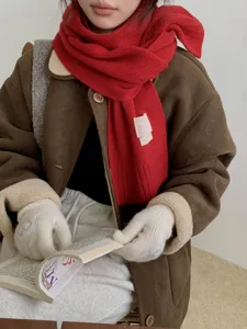 Gros plan détaillé d'un écharpe en tricot rouge associée à une veste d'hiver élégante.