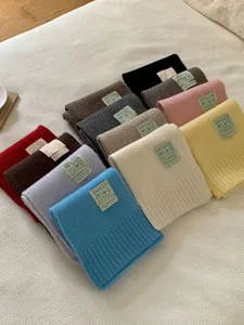 Gros plan de foulards en tricot de laine colorés pliés proprement, texture douce et accessoires d'hiver.