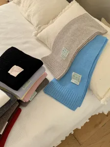 Vue détaillée d'écharpes en tricot douillet de diverses couleurs avec étiquettes cousues.