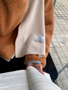 Closeup detail view of the soft knit scarf with woven brand tag, cozy winter apparel.
