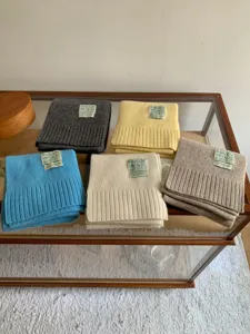 Gros plan détaillé de foulards en tricot colorés pliés avec étiquette sur table.