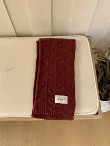 Chunky knit scarf detail showing dark red cable pattern texture and cozy winter warmth.