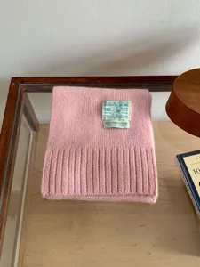 Écharpe en tricot rose douillette avec texture côtelée classique et étiquette rétro pour l'hiver.