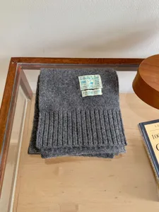 Écharpe tricotée grise d'hiver avec étiquette, tissu doux et confortable pour temps froid.