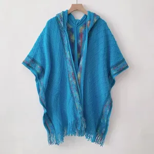 Blue hooded knit poncho shawl with colorful trim tassel detail hanging on wooden hanger close up