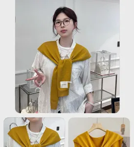 Detail view of yellow knit shawl scarf worn over striped shirt, versatile office accessory.