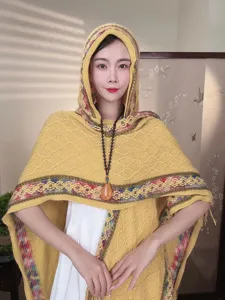 Detail view of ethnic style women's knitted hooded shawl in yellow, cozy and elegant design.