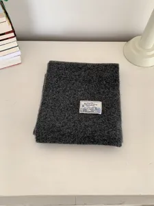 Detailed view of a dark grey knitted winter scarf, soft texture with a brand label.