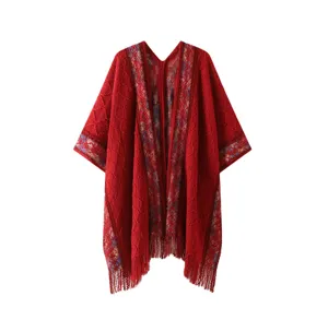 Red knitted cape detail, fringe hem, ethnic woven trim, cozy outerwear closeup, boho fashion style.