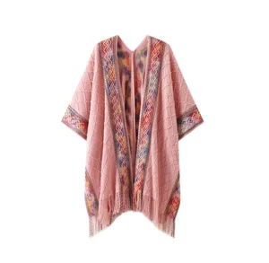 Detailed view of the pink knitted poncho featuring colorful ethnic trim and elegant fringe hem.