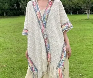 Detailed view of the stylish hooded knitted poncho with ethnic geometric patterns and fringe.