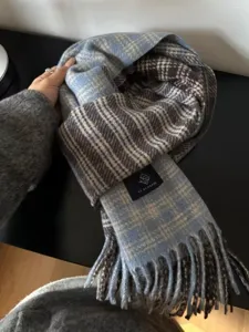 Gros plan détaillé sur l'écharpe d'hiver à carreaux bleu et marron avec franges.