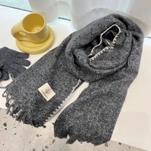 Dark grey textured winter scarf detail, soft woven knit fabric with cozy fringe and custom label.