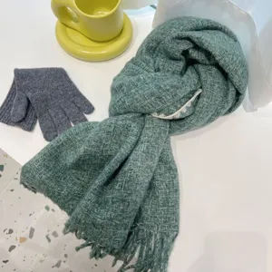 Detailed close-up view showing the thick green knitted scarf texture and delicate fringe design.