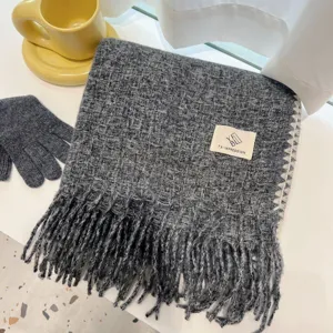 Detailed view of a cozy dark grey winter scarf with chic fringes and a woven label design.