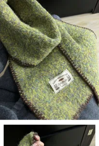 Detailed shot of green knit scarf texture, soft warm winter neck warmer fabric showcase.