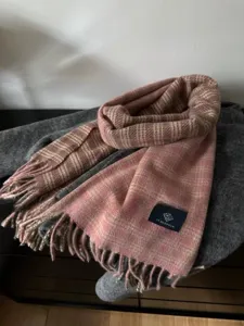 Gros plan détaillé de l'écharpe en tricot à carreaux rose et marron avec texture et franges.