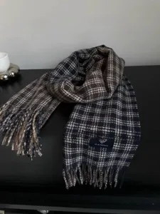 Gros plan détaillé d'une écharpe d'hiver à carreaux bleus et marrons avec franges.