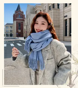 Outdoor detail view of a soft winter tassel scarf in stylish haze blue, cozy fashion look.