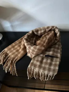 Gros plan détaillé d'une écharpe à carreaux marron et beige montrant sa texture douce.