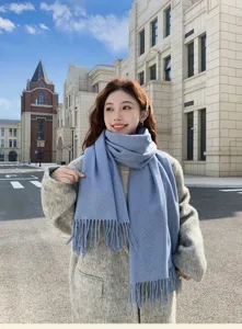 Haze blue winter scarf detail, cozy knitted fringe texture shown in outdoor street scene.