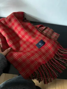 Détail d'écharpe à carreaux rouge et marron douce avec franges pour l'hiver chaleureux.