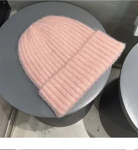 Detailed close-up of soft pink knitted beanie hat showing cozy ribbed texture and rolled cuff.