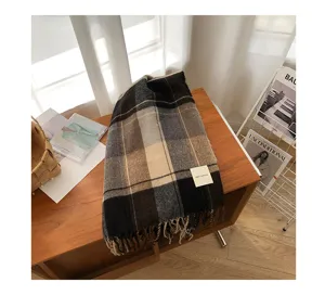Detailed view of a vintage Korean style plaid fringe scarf in cozy autumn winter tones on a table.