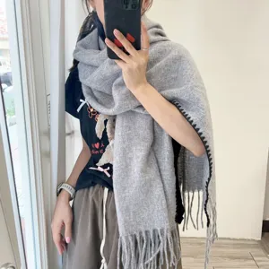 Detail view of the thick grey winter scarf with stylish black fringe edge and soft texture.