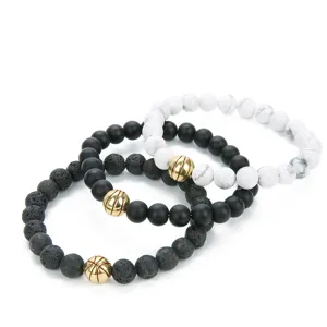 Close-up of stacked beaded bracelets with lava stone, white turquoise, and gold basketball charms.