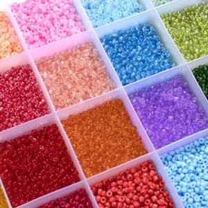 Perles de rocaille en verre multicolores dans une boîte de rangement, idéal pour bijoux DIY.