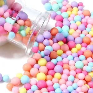 Gros plan de perles rondes colorées de macaron versées d'une bouteille en verre.