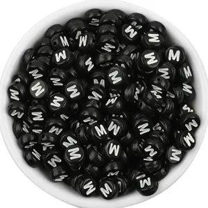 Close-up detail of black acrylic flat round letter beads with white M print for DIY jewelry.