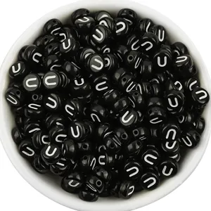 Close up of black acrylic flat round letter beads with white letter U for DIY jewelry making.