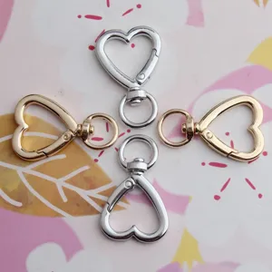 Close-up of alloy heart-shaped swivel snap hooks and keychain clasps in silver and gold.