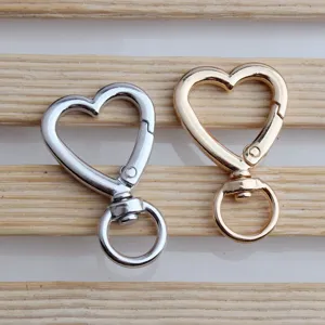 Close-up of heart-shaped alloy keychain clasps in silver and gold with swivel rings.